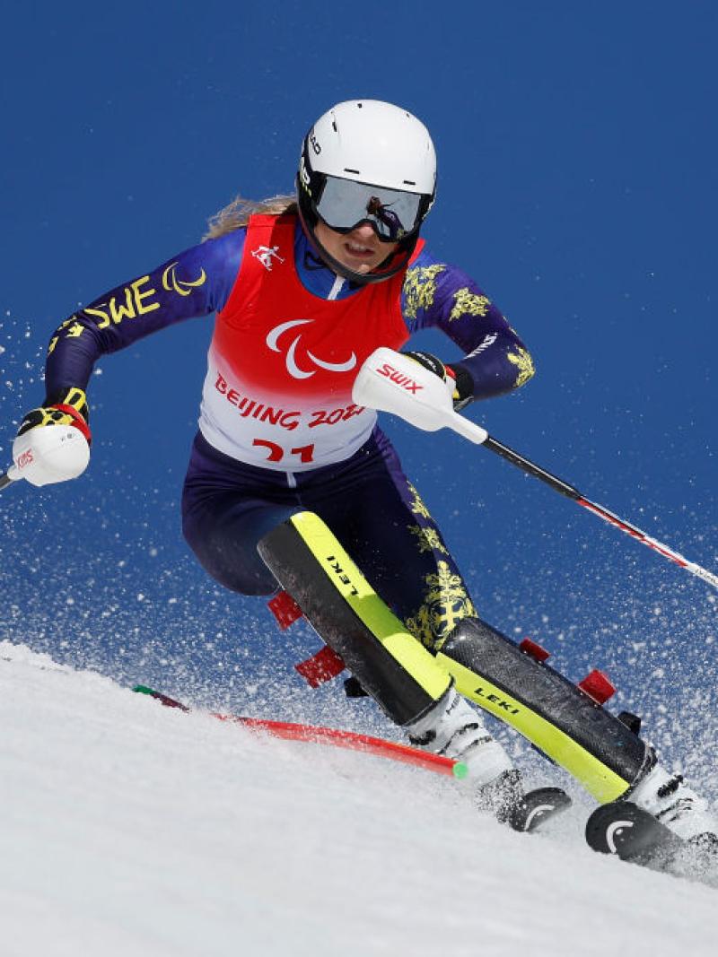 A female Para alpine skiing athlete in action.