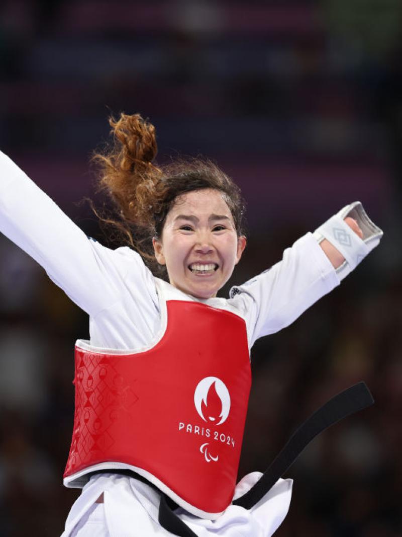 A female Para taekwondo athlete is celebrating.