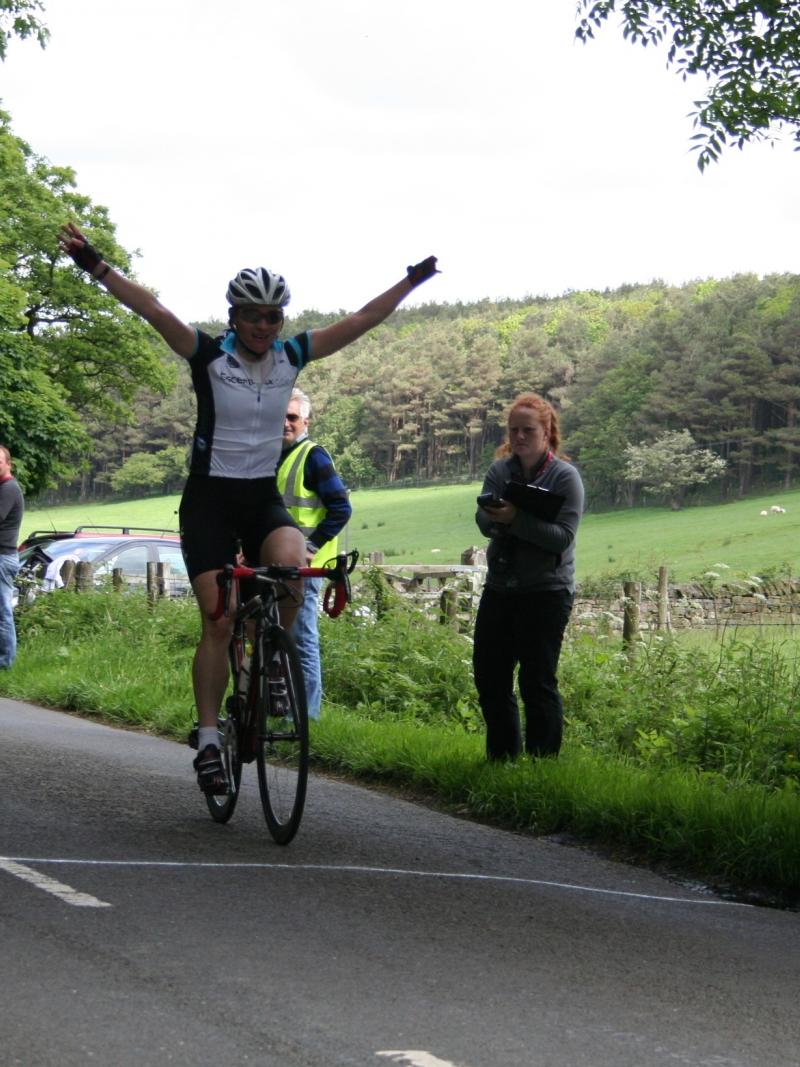 A picture of a woman on a cycle celebrating her victory