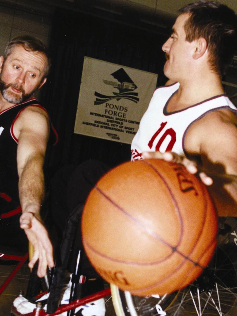 A picture of 2 men in a wheelchair playing basketball