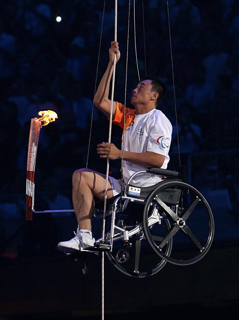 A picture of a man in wheelchair climbing with a torch