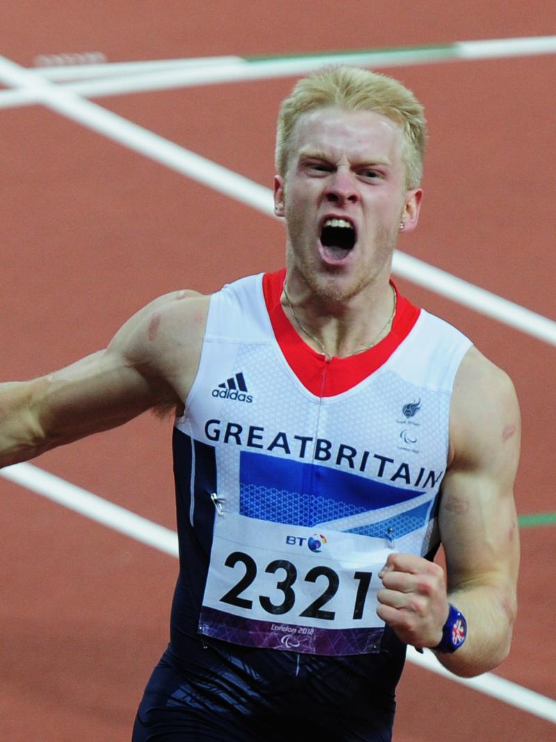 A picture of a man crossing a finish line during an athletics race and celebrating his victory