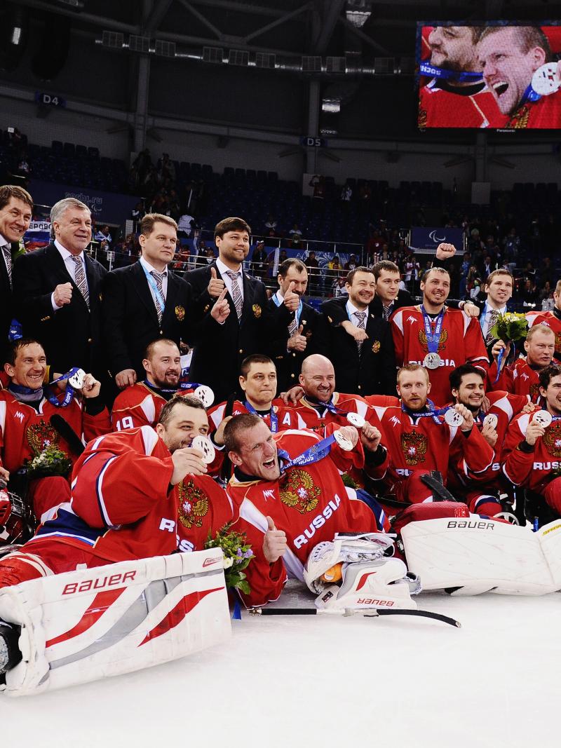 The entire Russian ice sledge hockey team poses with their medals on the ice facing the camera. 