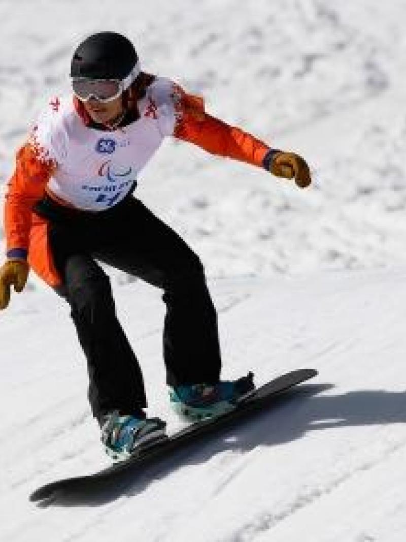 A female snowboarder rides down a slope