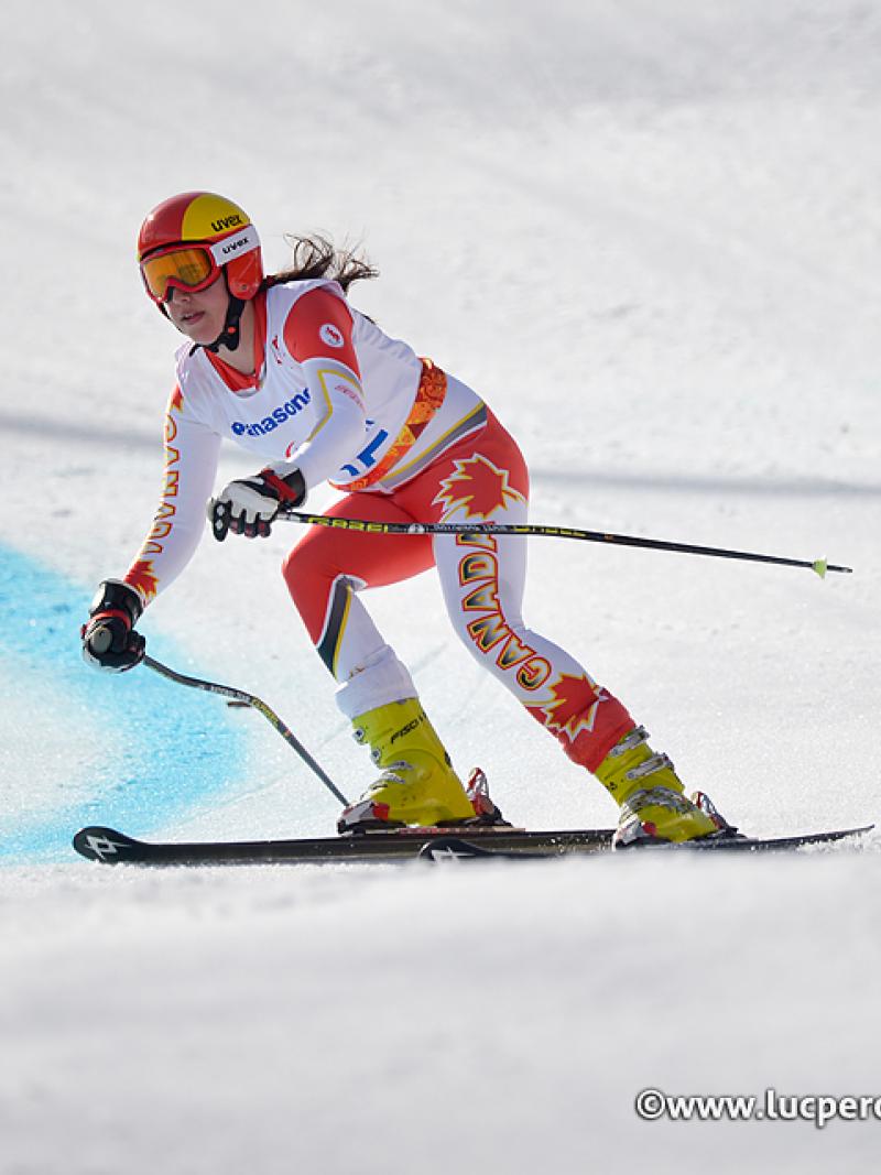 Skier in orange and white ski suit, skis at speed down slope