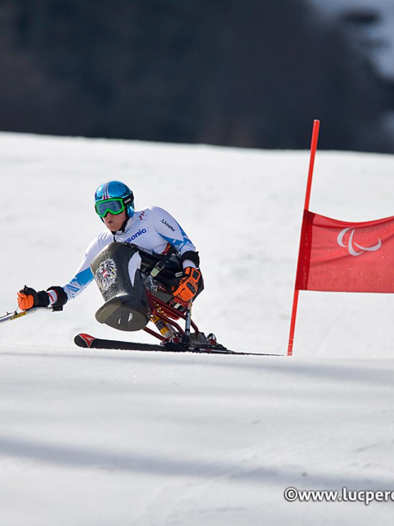 Woman in sit ski on a slope passing a gate