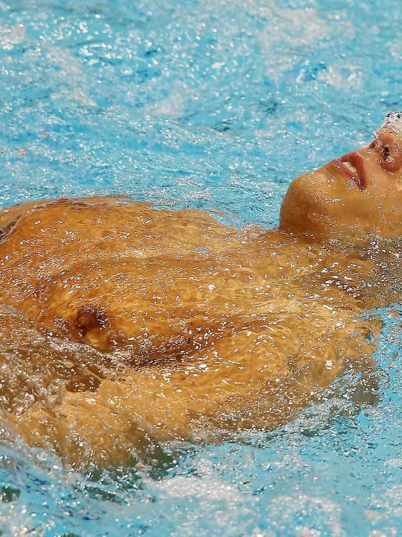 A swimmer wearing goggles laid on his back in the water at the start of a race.