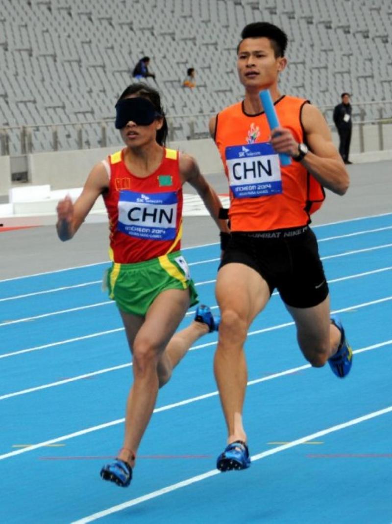 Blindfolded women with guide running in a relay