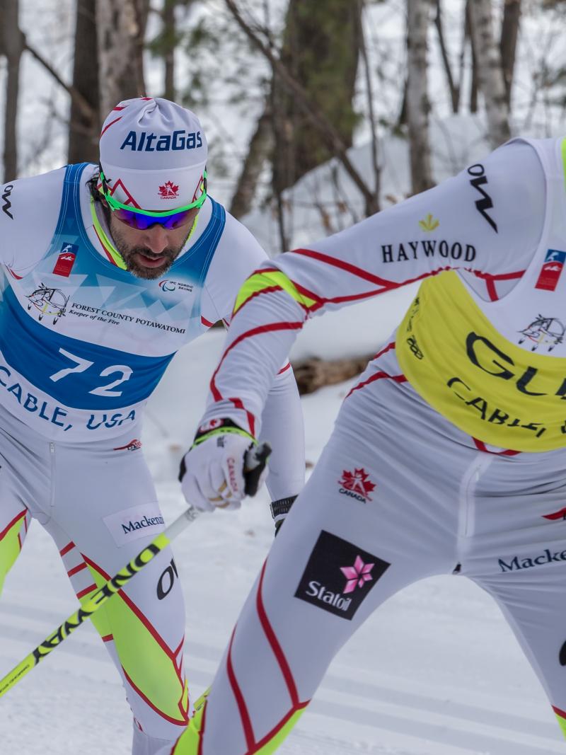 cross country skier and guide climb up a hill