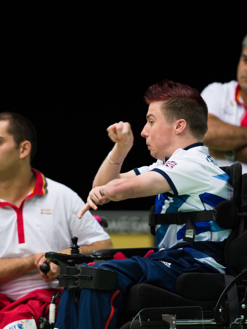 Two men in wheelchairs, one throwing a blue ball