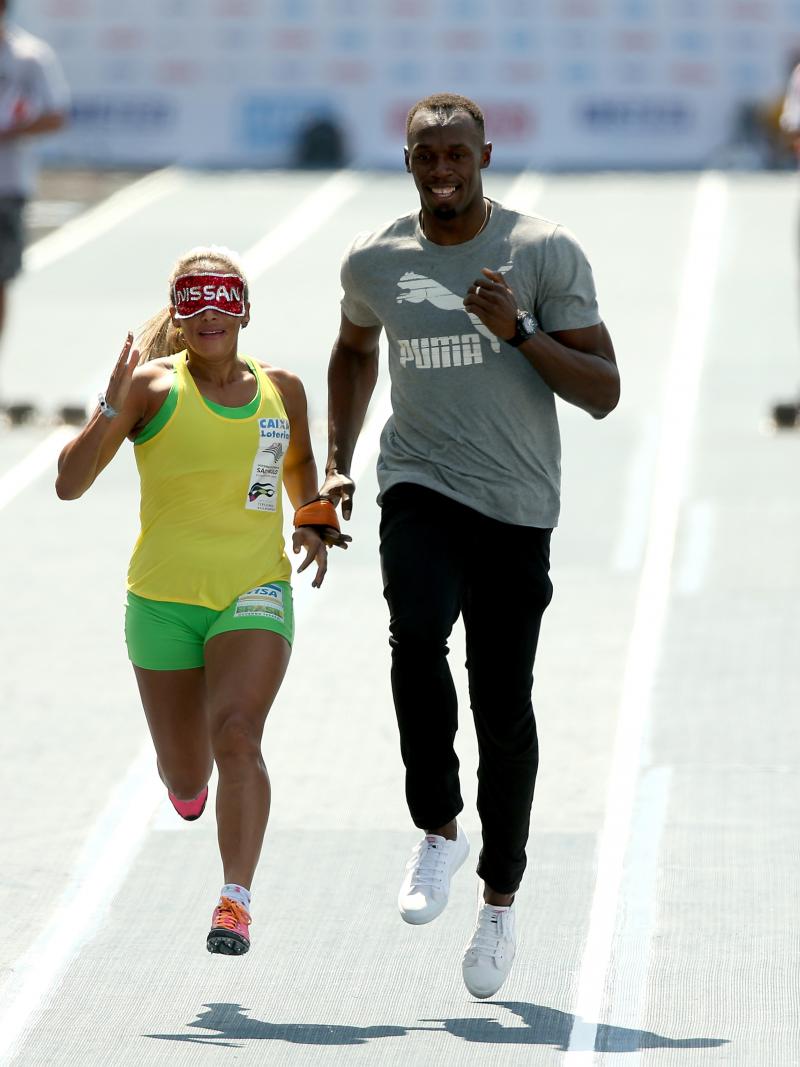 Brazilian Paralympian Terezinha Guilhermina runs with Usain Bolt of Jamaica as her guide during an exhibition in preparation for the Mano a Mano Athletics Challenge at the Jockey Club Brasileiro in Rio de Janeiro, Brazil.