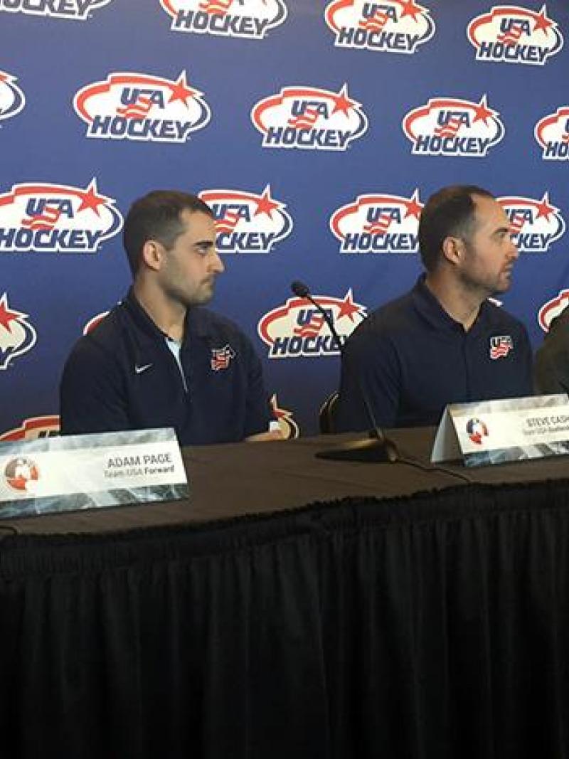 Three players and two men in training suits on a podium