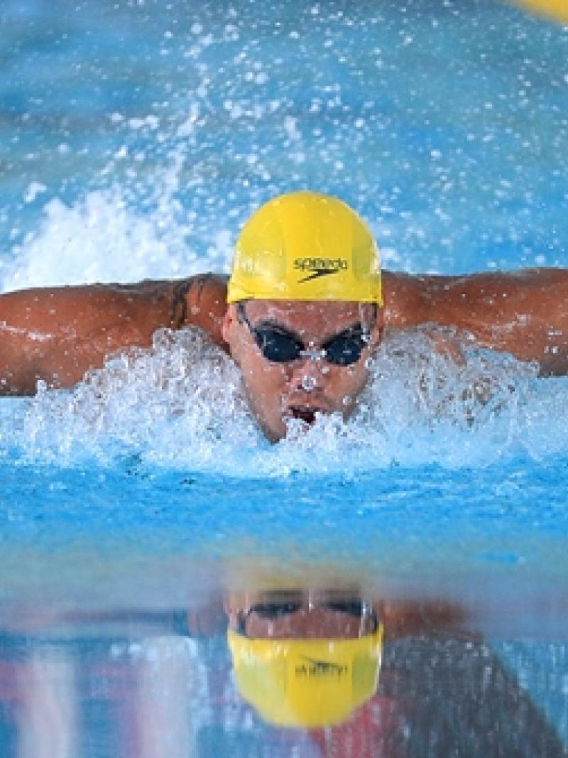 Man with yellow sim cap swimming butterfly