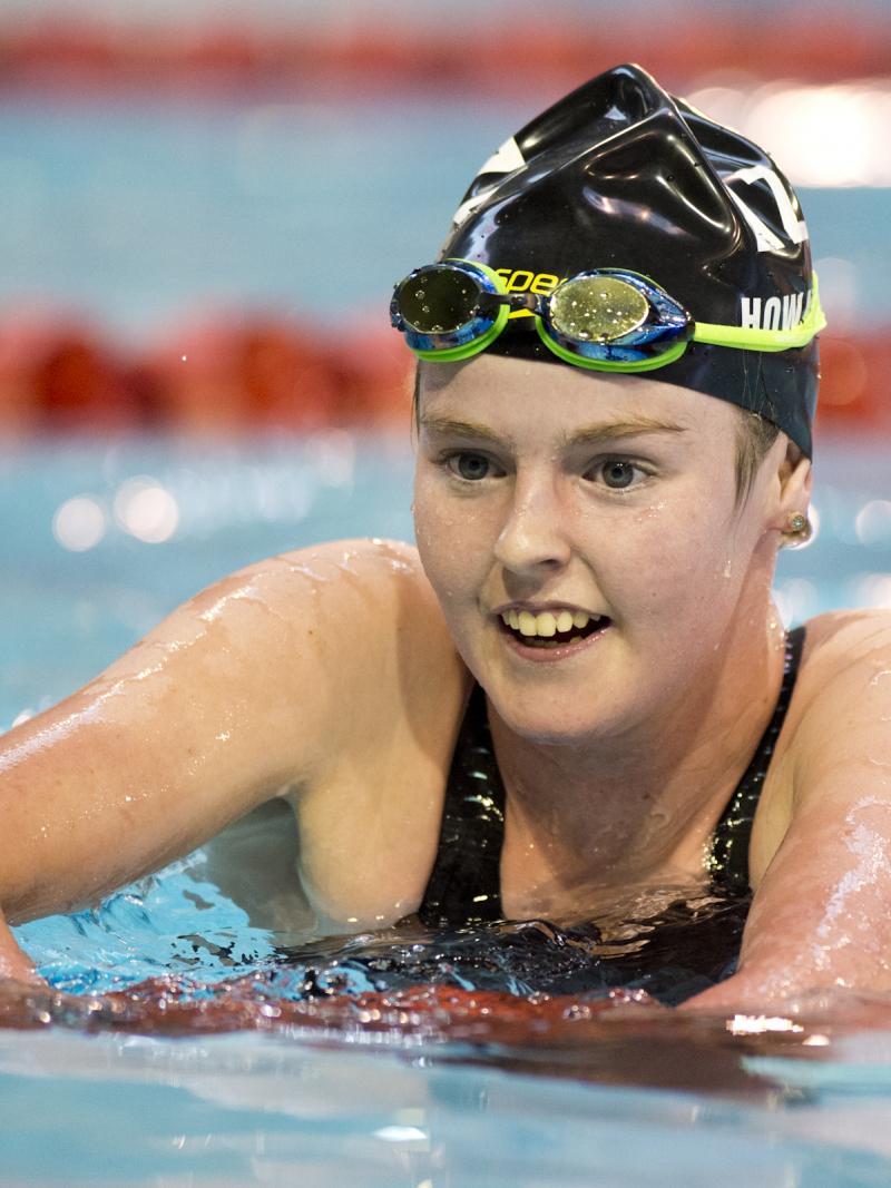 Woman in swimming pool, upper body is out of the water, smiling