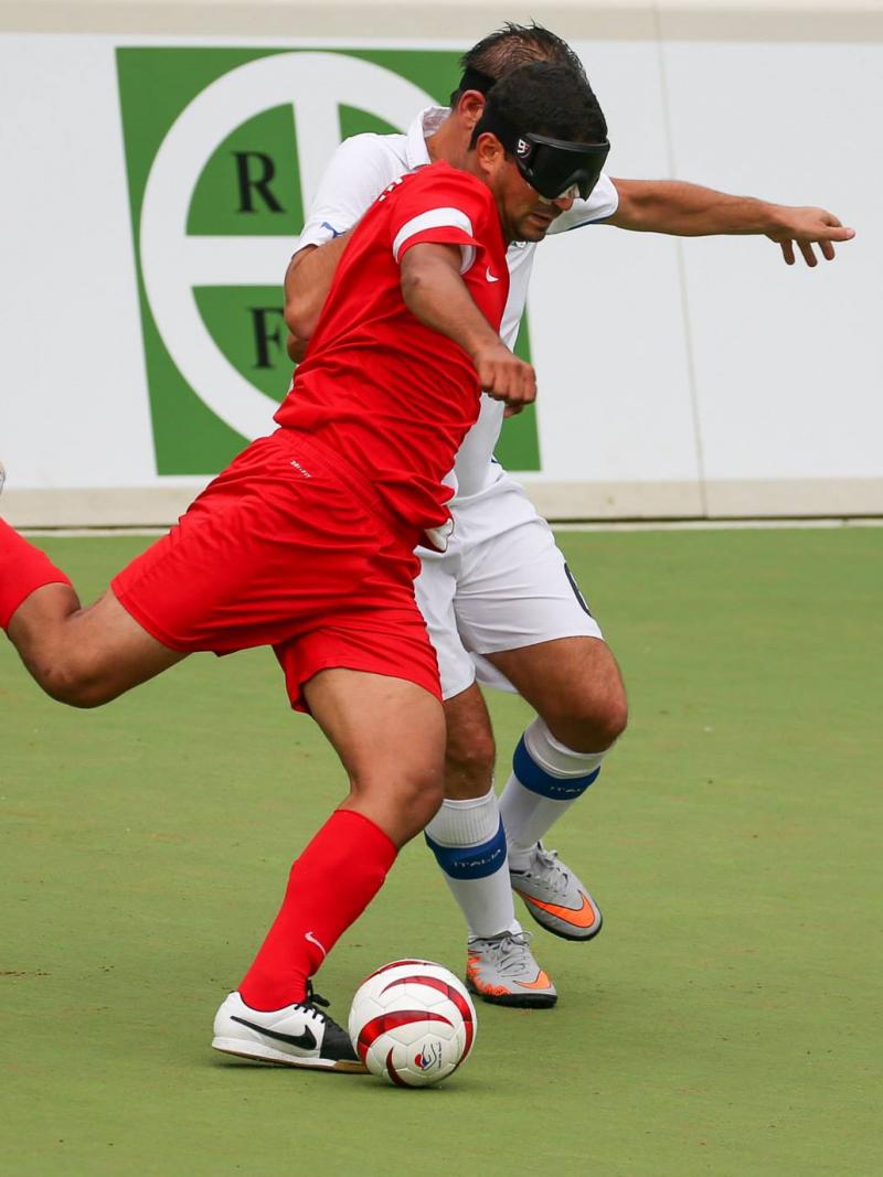 Two blindfolded football players fight for the ball