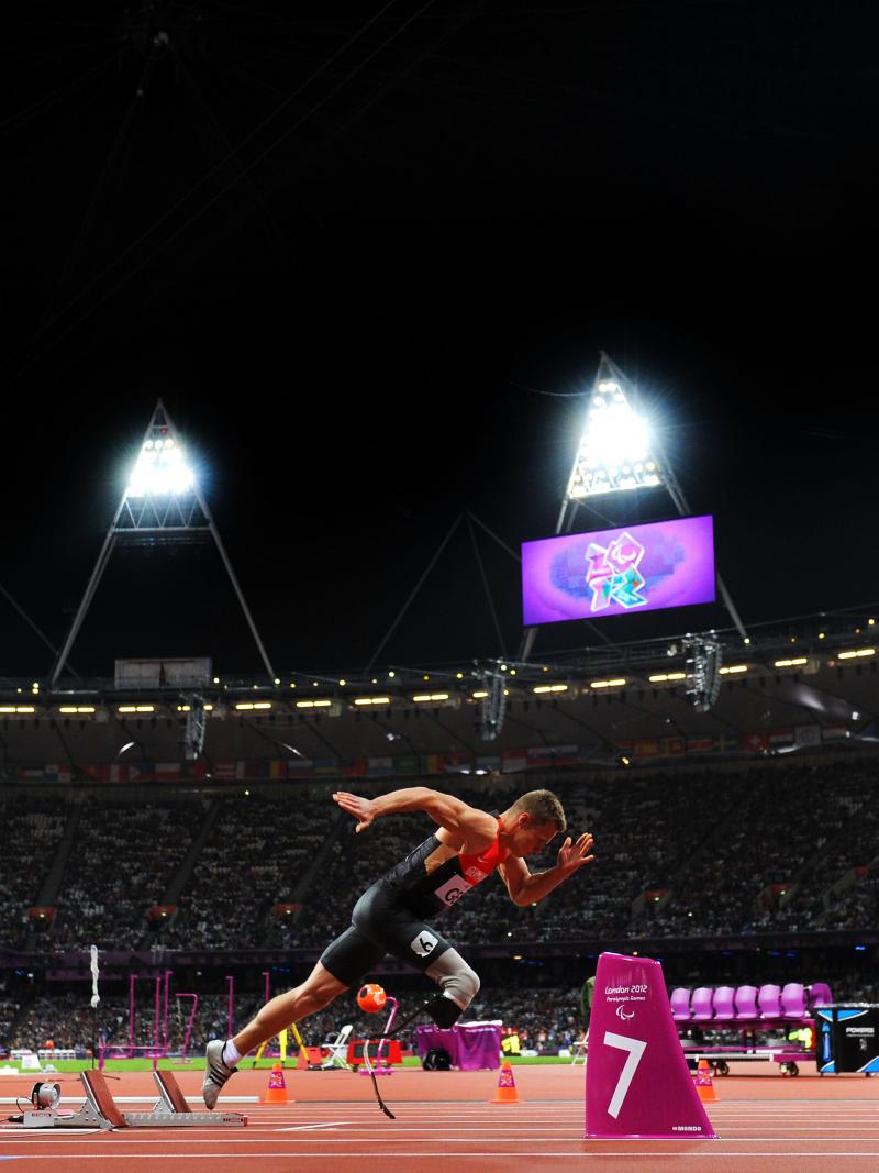 Man in a full stadium, starts sprinting from starting blocks