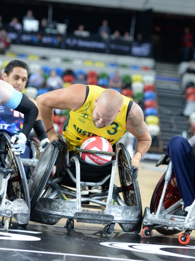 wheelchair rugby player in yellow jersey defending the ball