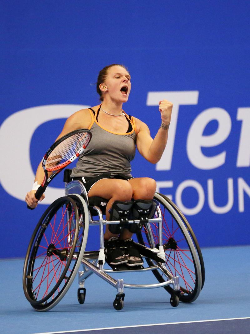 Woman in wheelchair celebrates after wheelchair tennis point