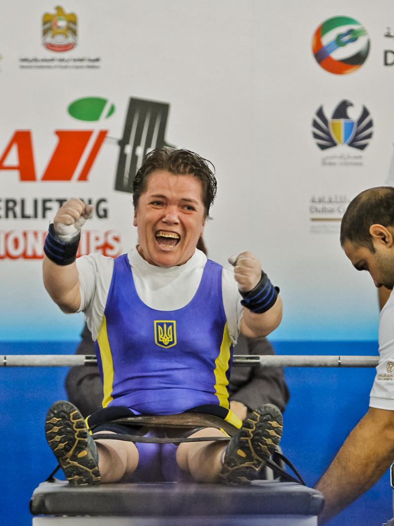 A powerlifter with short stature celebrates on the bench