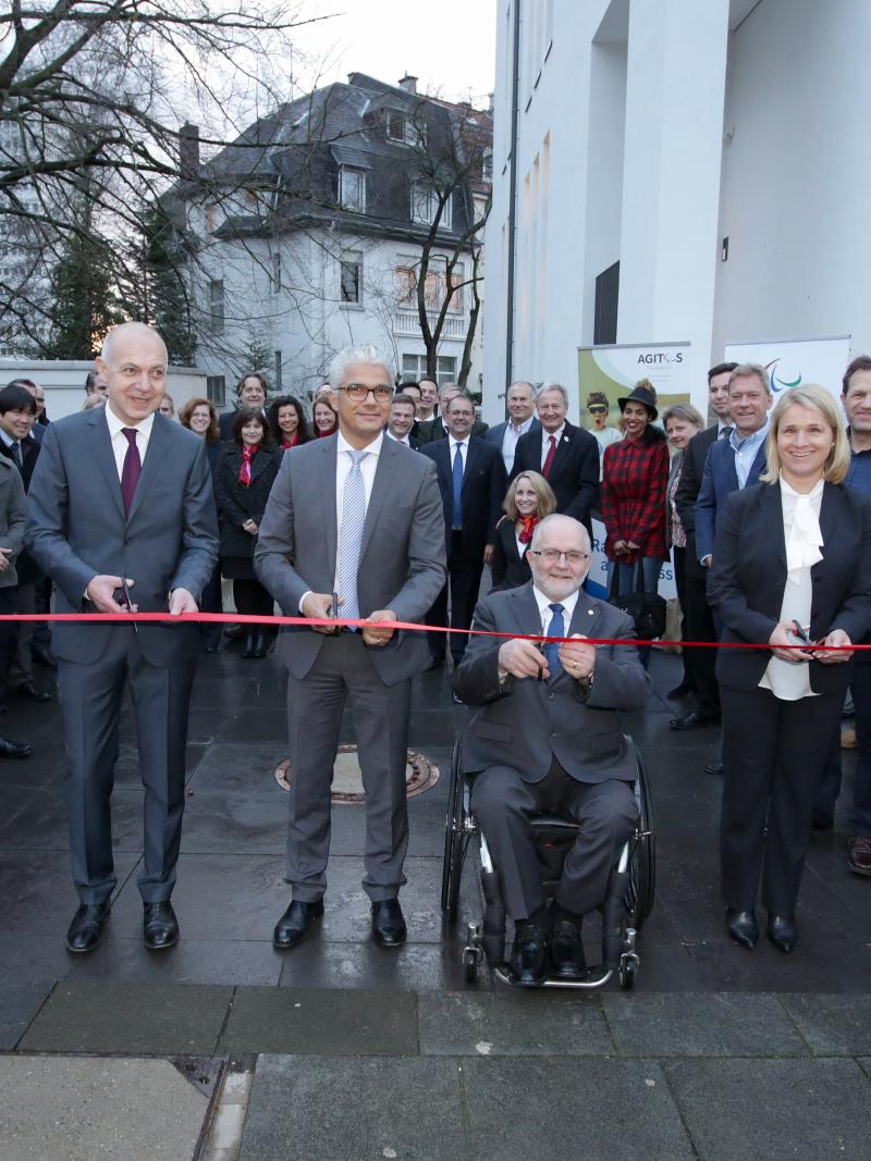 Picture of four people cutting a red ribbon to open a new building.