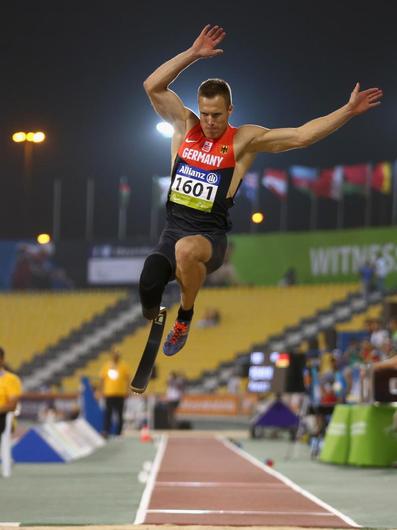 a male from Germany wearing red and black clothes competing in the long jump