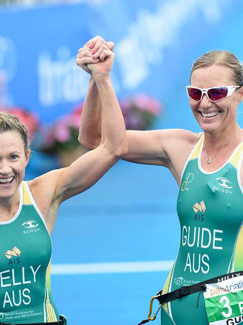 Two women in jerseys smiling and raising her arms