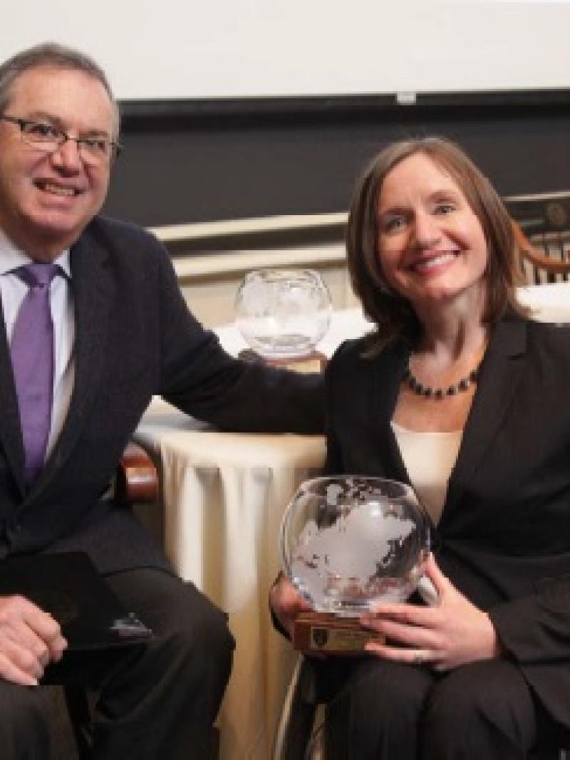 Woman in wheelchair holds trophy and poses with man.