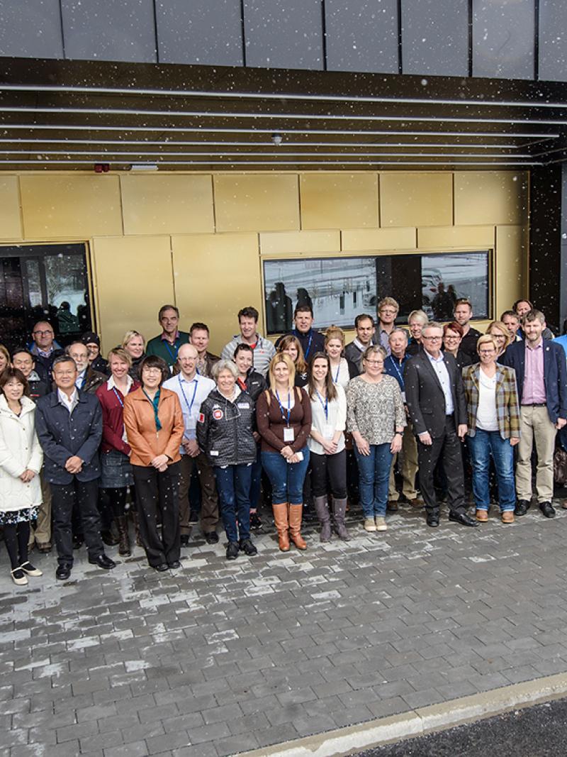 Group shot of 34 people outside a building. It's snowing