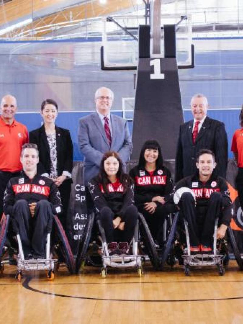 Twelve athletes in wheelchairs lined up, making up the wheelchair rugby team. 