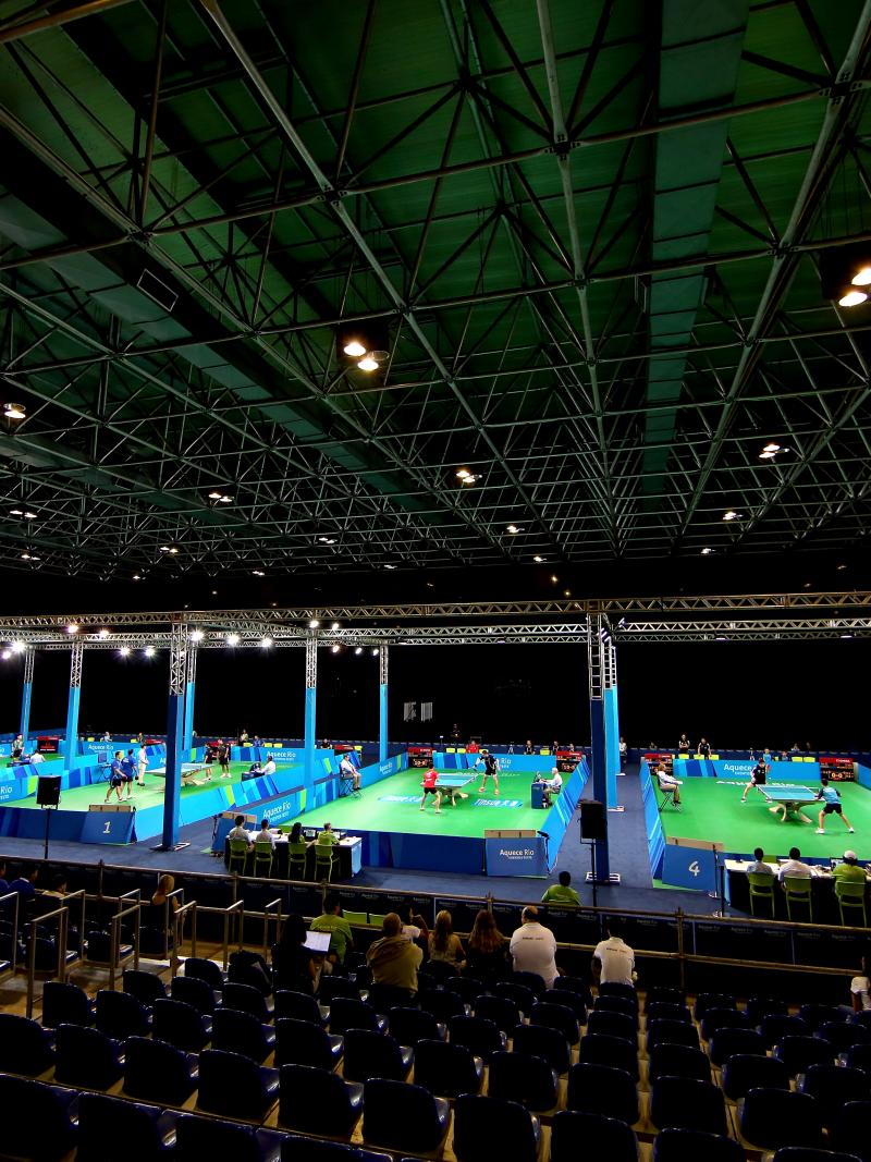 A look inside a venue where table tennis will be contested. On the court are four tennis tables set up.