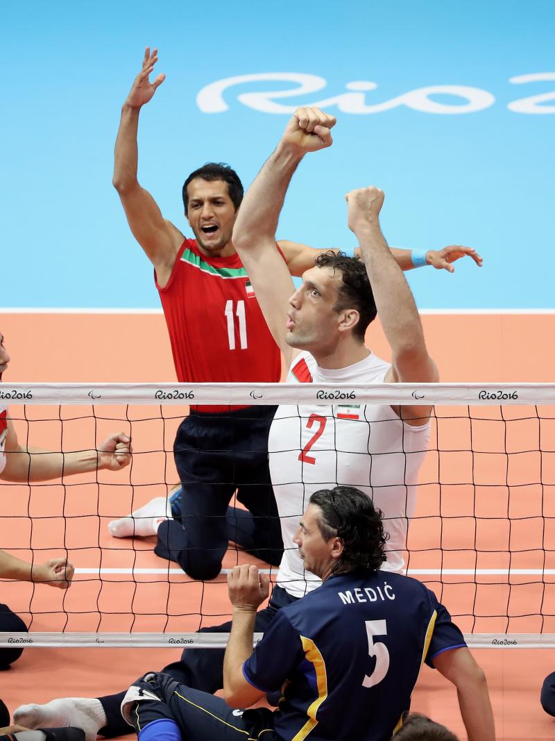 Group of sitting volleyball players celebrate after a point.