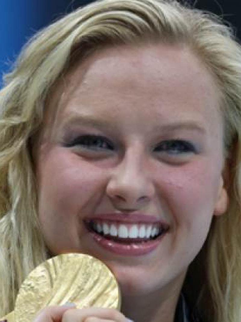 A portrait of a blond woman showing her gold medal