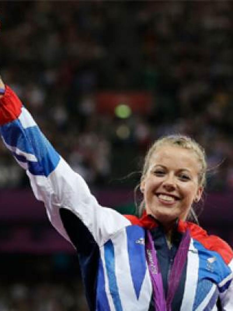 A picture of a woman showing her gold medal during a medal ceremony