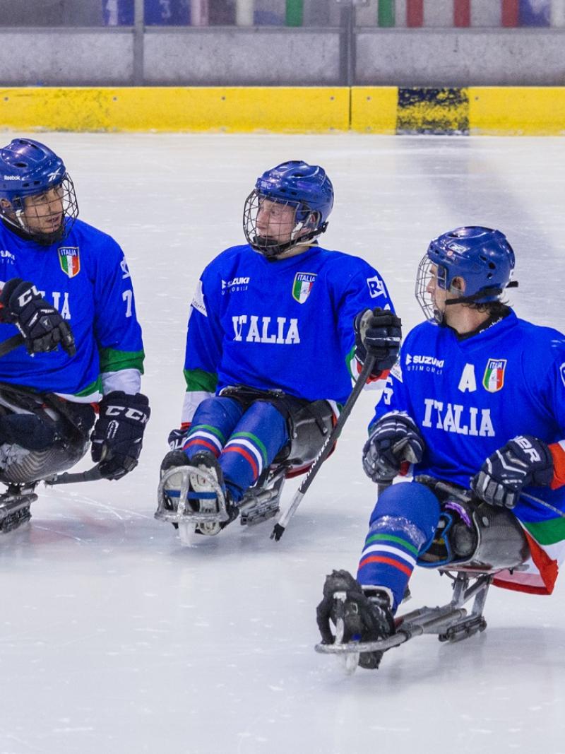 Three Para ice hockey players on ice talking to each other