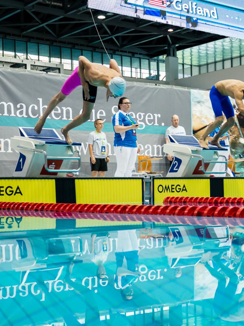 a group of men dive into a pool
