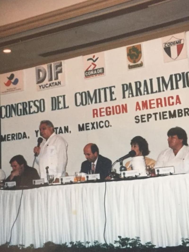 a group of men speak at a table