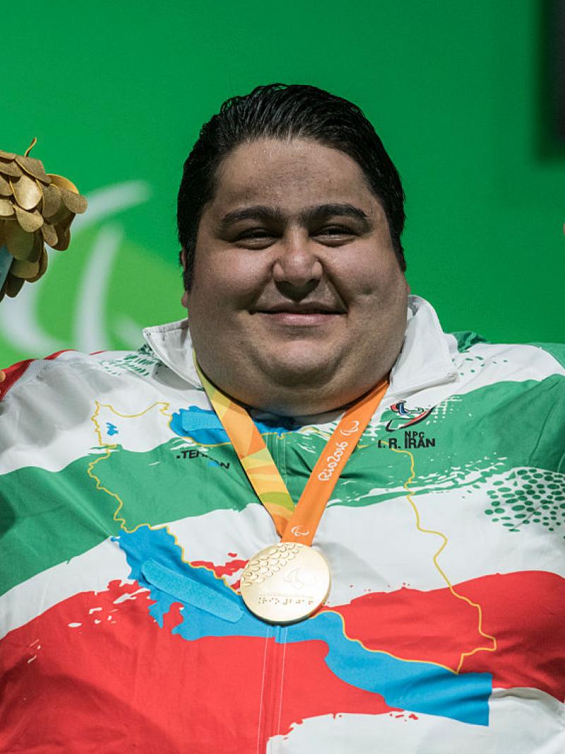 a male Para powerlifter smiles with his medal