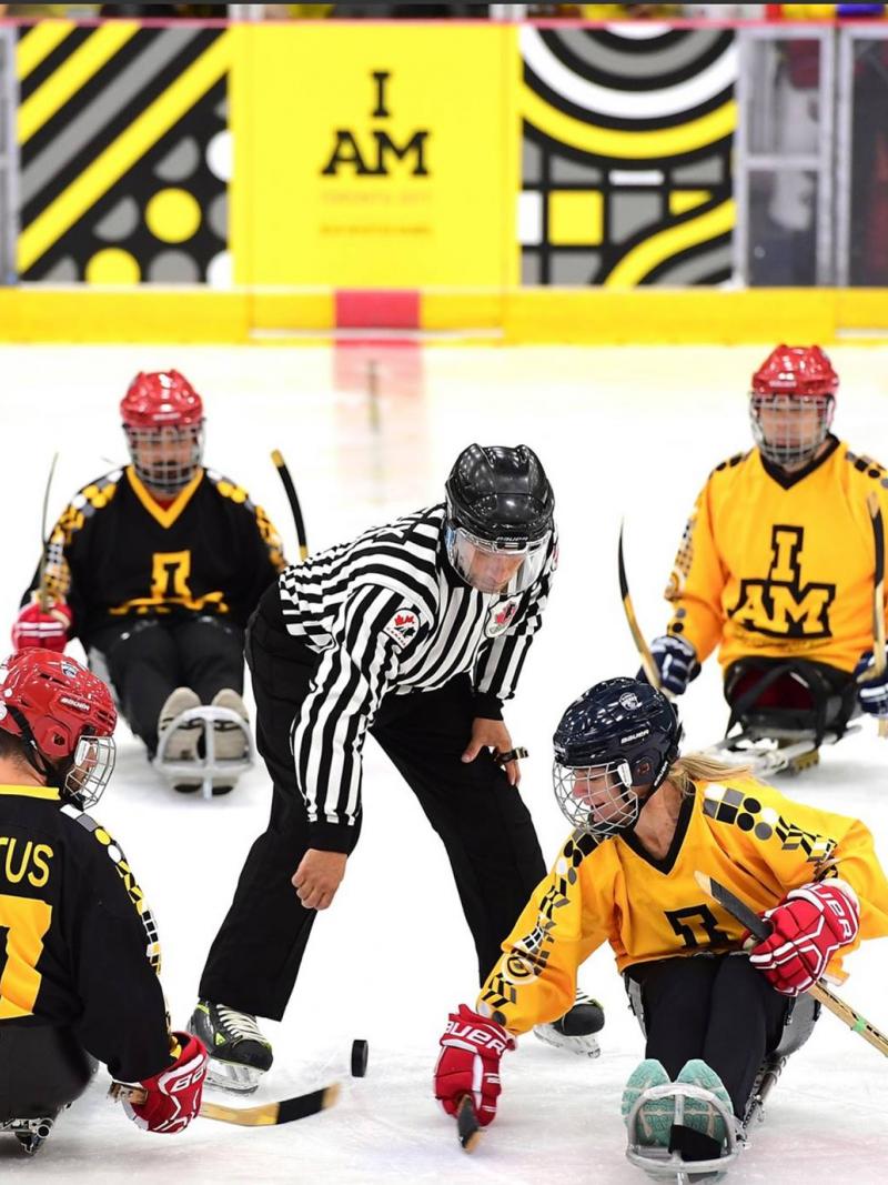 a group of Para ice hockey players take instruction from a referee