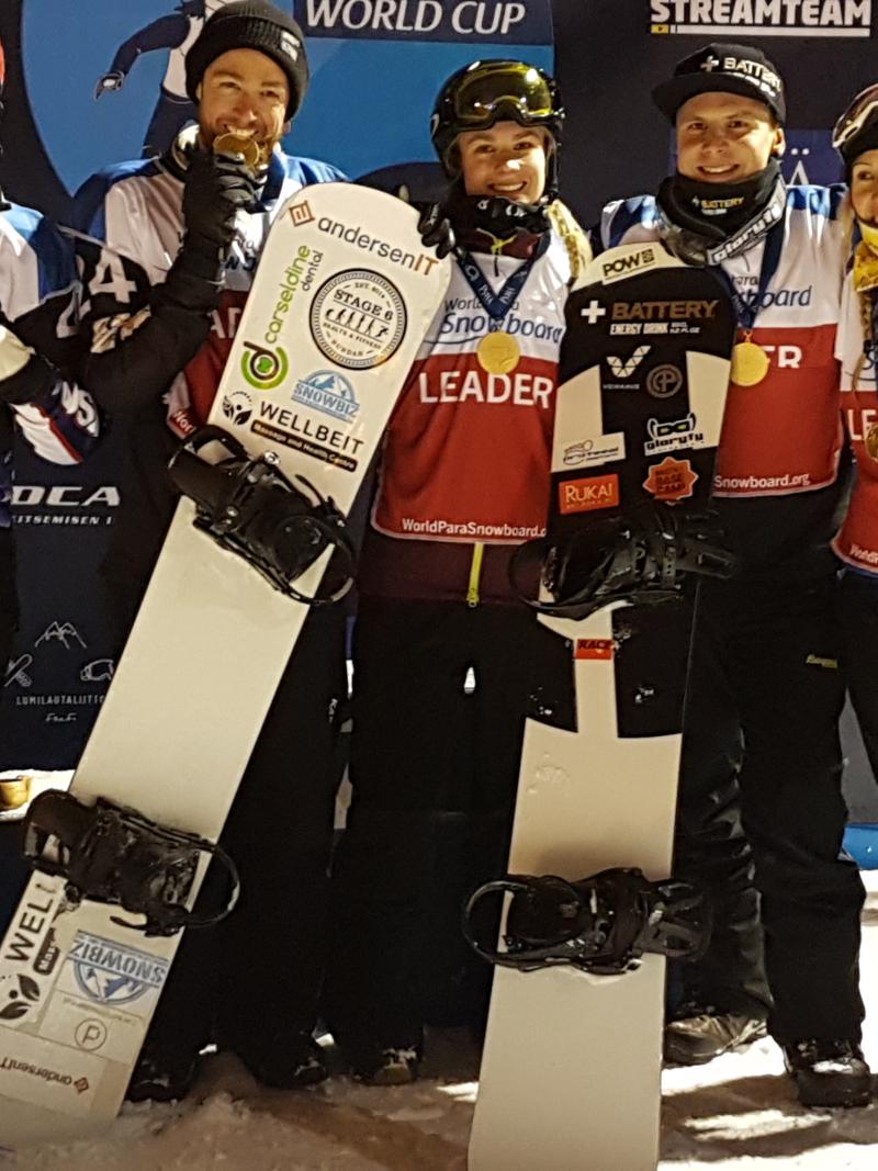 a group of Para snowboarders smile with their medals