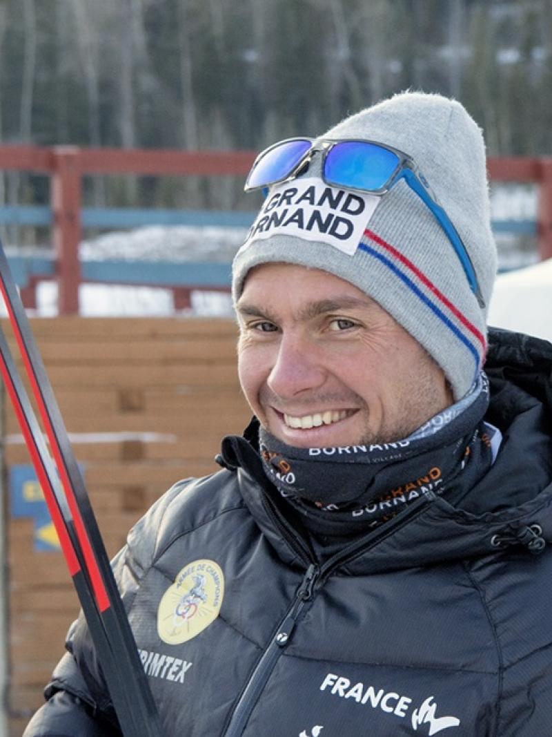 a male Para skier smiles at the camera while holding his skis