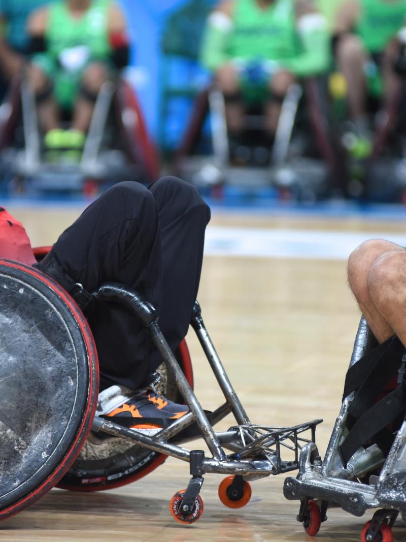 two male wheelchair rugby players clash for the ball