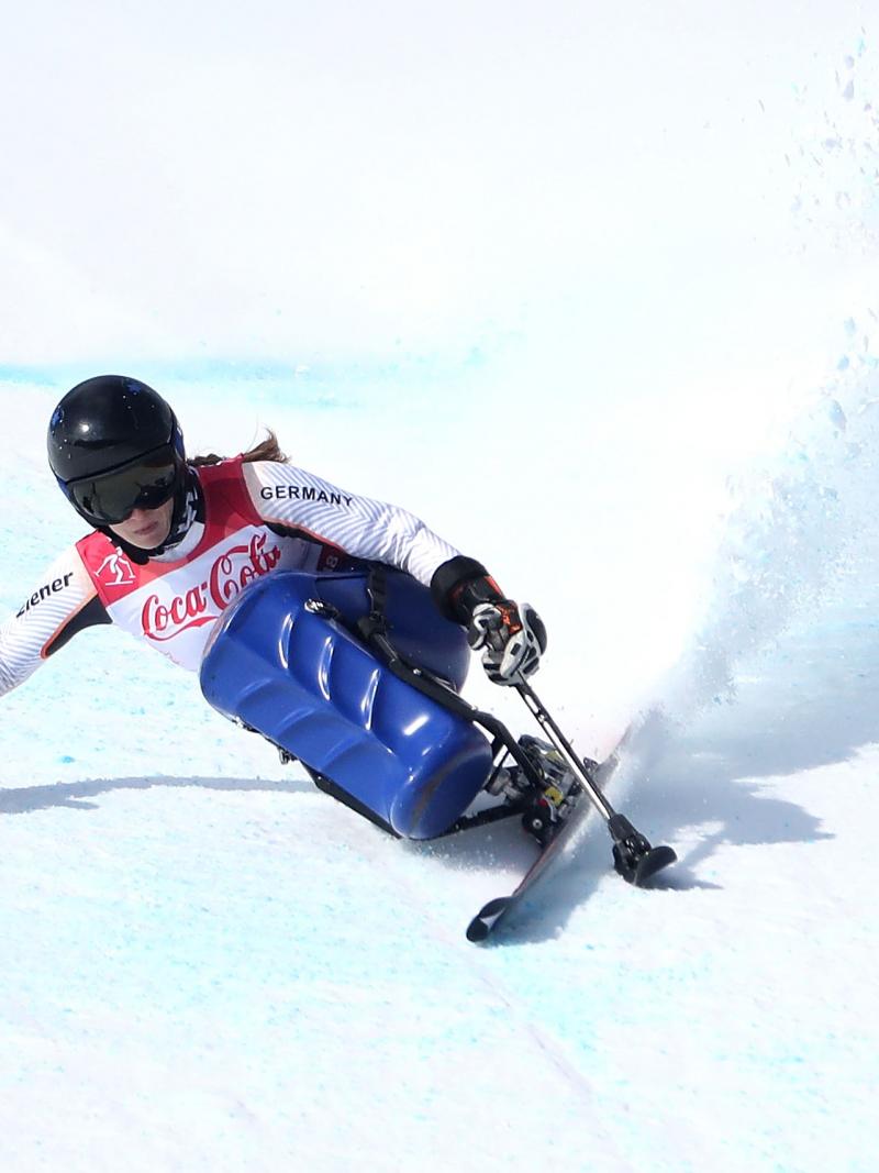 a female sit skier rounds a gate