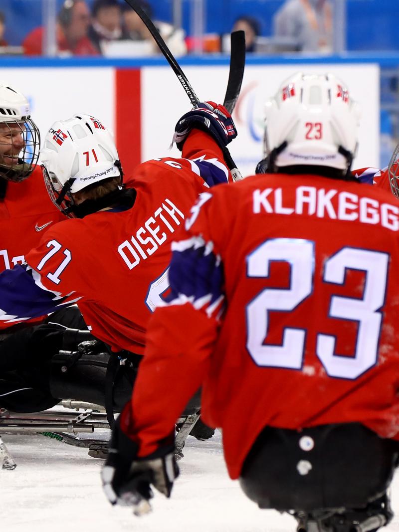 a group of Para ice hockey players celebrate a goal