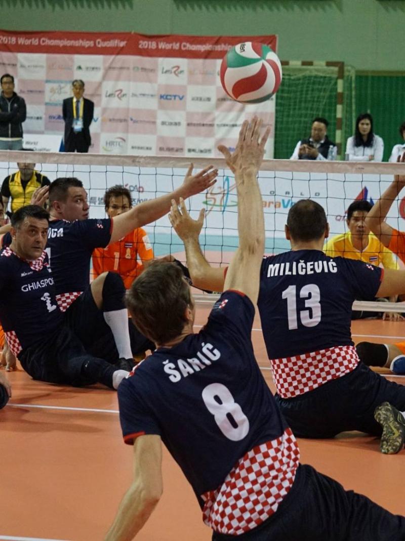 a group of male sitting volleyball players in action on the court