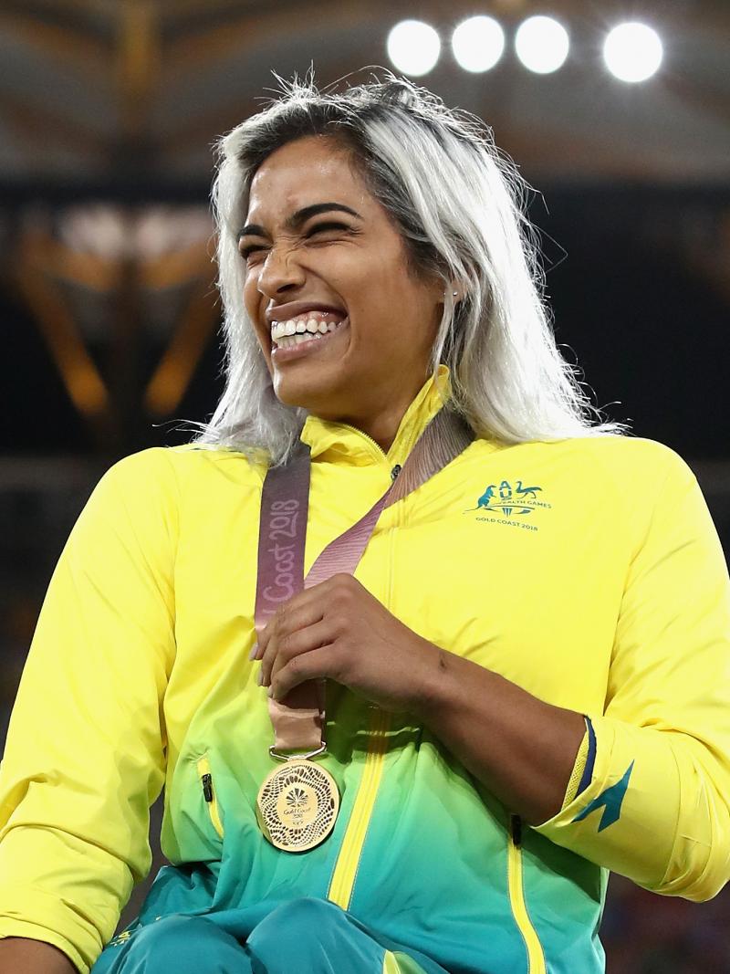 a female wheelchair racer laughs with her gold medal