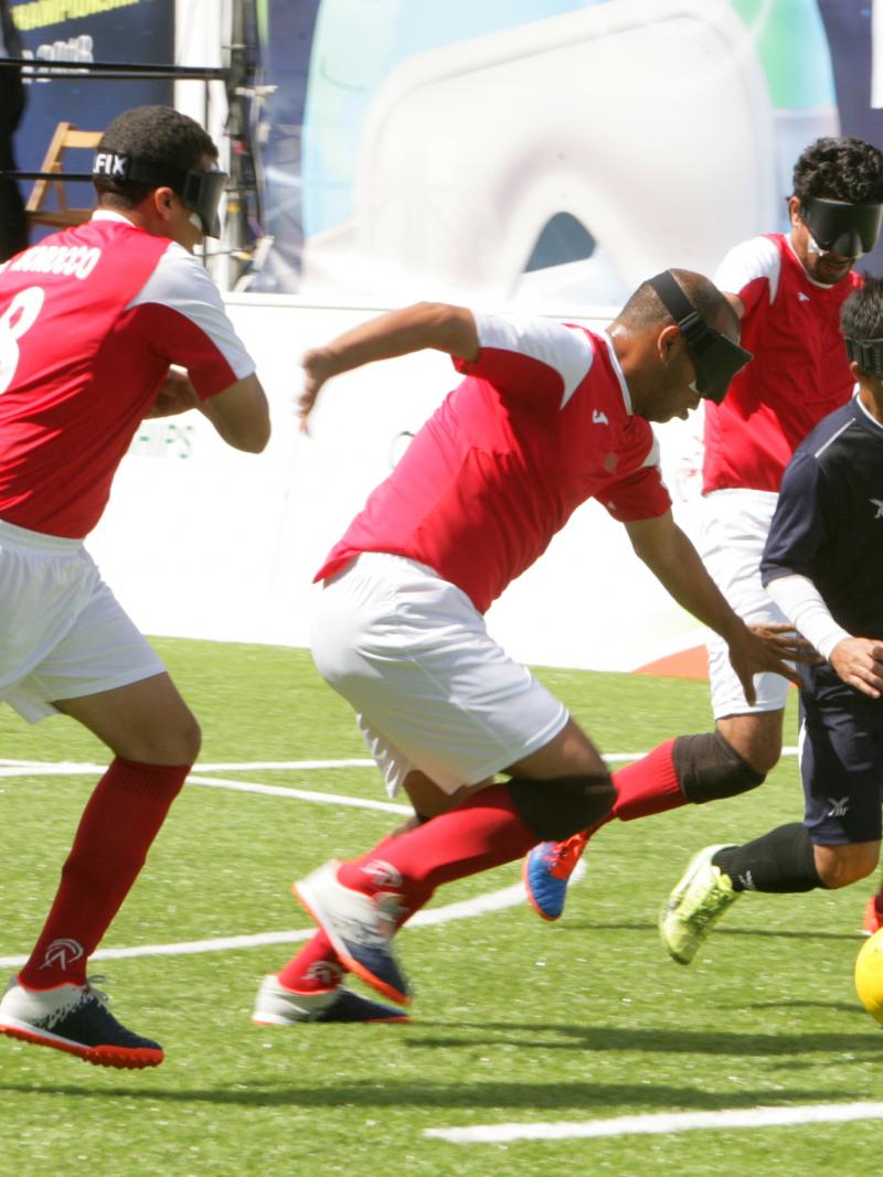 a group of blind footballers contesting a ball
