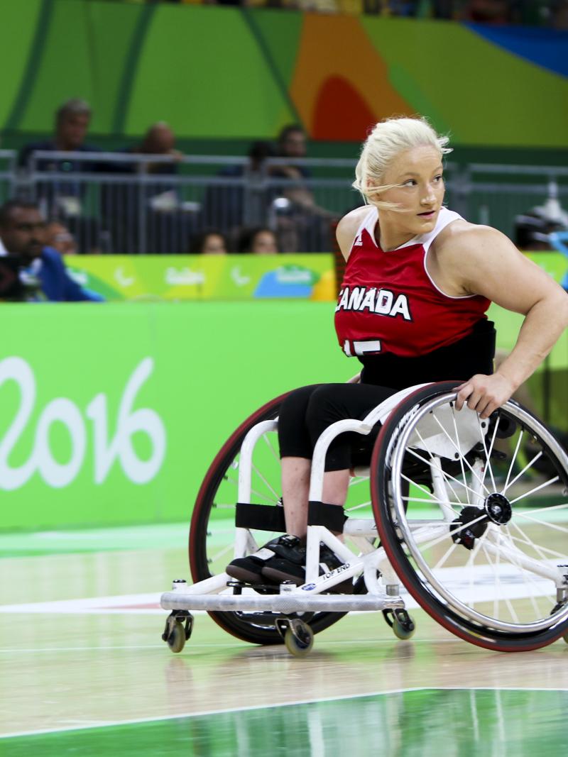 Women in wheelchair dribbles basketball