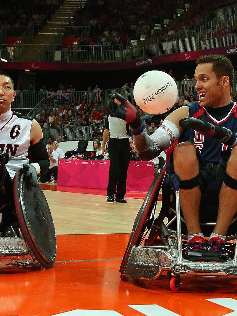 two male wheelchair rugby players with one holding a ball 