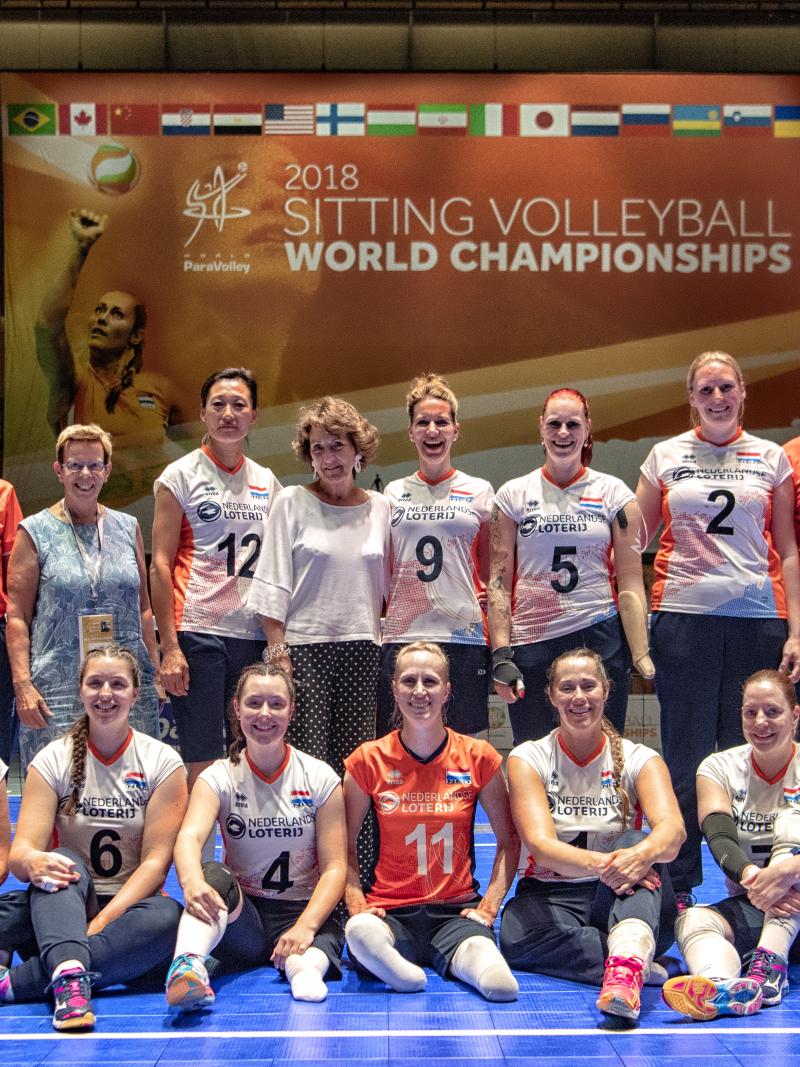 Princess Margriet and a group of female sitting volleyball players grouped together on a court