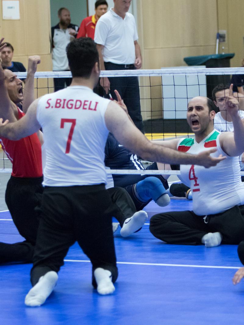 The Iranian men's sitting volleyball team throw their arms up in celebration on the court